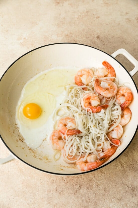 This easy homemade Pad Thai recipe is a lightened up version of the original made with shrimp, eggs, and tofu. Dinner’s done in 25 minutes! Egg cracked into wok with shrimp and noodles