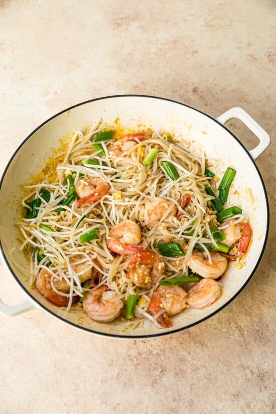 This easy homemade Pad Thai recipe is a lightened up version of the original made with shrimp, eggs, and tofu. Dinner’s done in 25 minutes! Shrimp and noodles in wok after adding bean sprouts