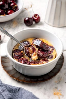 Spoon digging into cherry clafoutis.