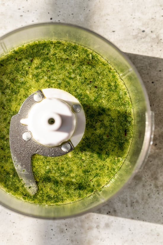 This fresh basil pesto is made with basil, garlic and Parmesan. Leaving out the pine nuts and reducing the olive oil makes it lighter! Homemade basil pesto in food processor bowl