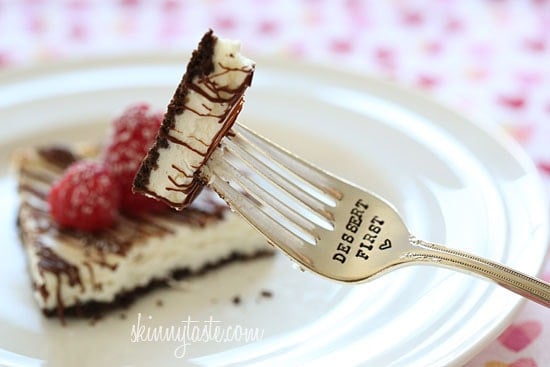 Cheesecake squares, lightened up with yogurt and light cream cheese, baked on a chocolate graham cracker crust drizzled with melted chocolate and topped with fresh raspberries.