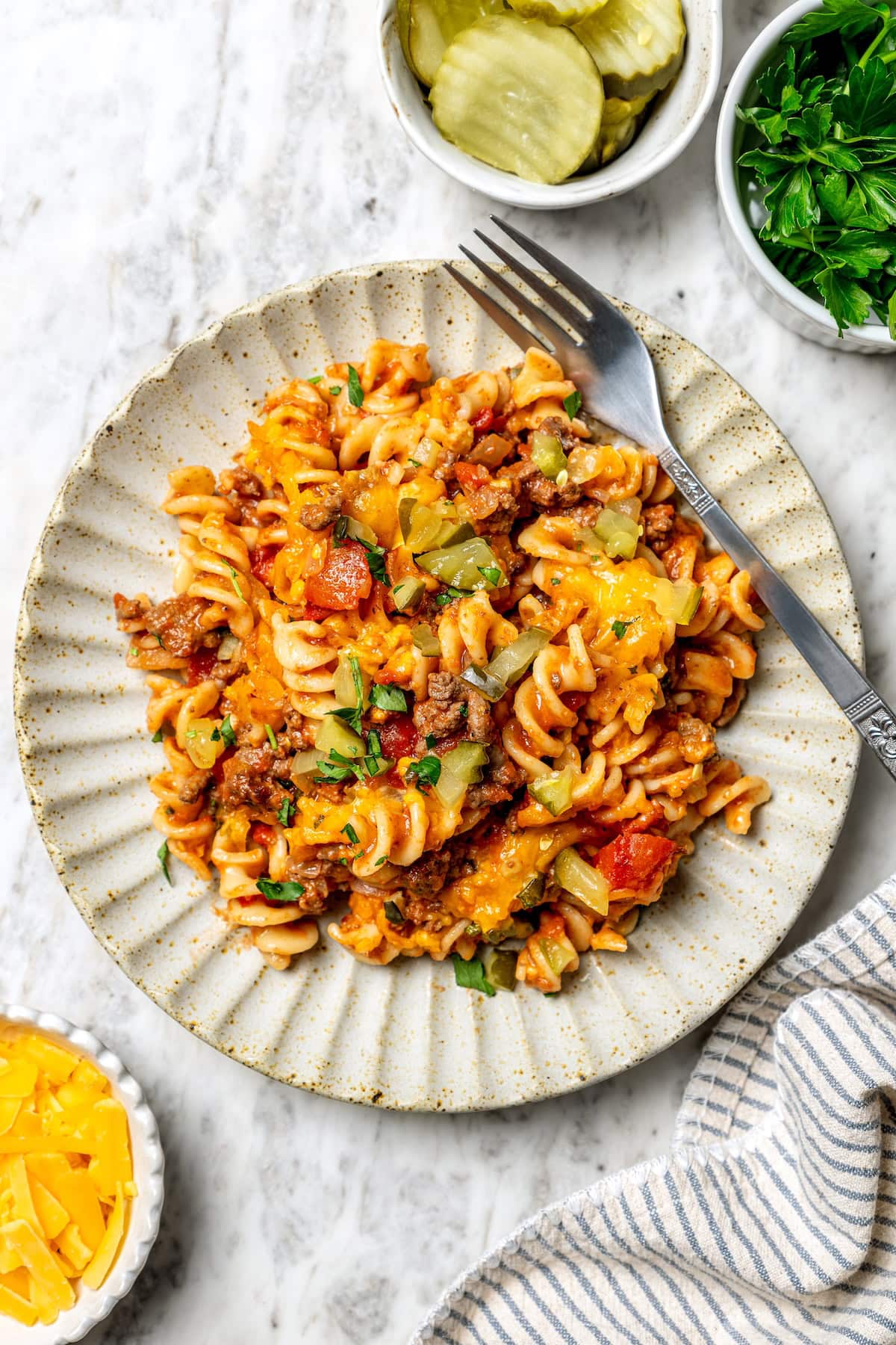 With ground beef, tomatoes, pickles, and cheese, this lightened up cheeseburger casserole recipe is kid-friendly and so delicious! Overhead view of cheeseburger casserole on plate with fork