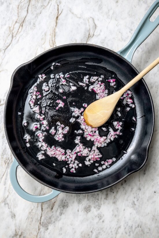 Eggs in purgatory is a simple Italian dish that simmers eggs in a fiery tomato sauce. My version is made with harissa for extra flavor! Cooking red onions in skillet with oil