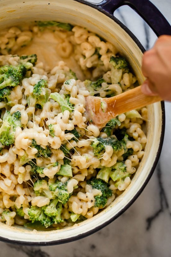 Creamy, cheesy, and packed with veggies, this lightened-up broccoli mac and cheese delivers kid-friendly comfort without feeling too heavy. Stirring broccoli macaroni and cheese in Dutch oven.