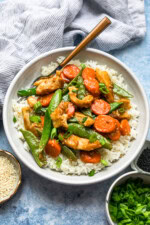 Overhead view of chicken and vegetable stir fry served over a bowl of rice.