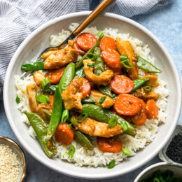 Overhead view of chicken and vegetable stir fry served over a bowl of rice.
