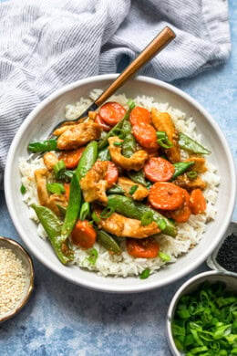Overhead view of chicken and vegetable stir fry served over a bowl of rice.