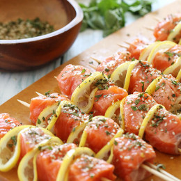 Salmon threaded onto skewers with lemon slices.
