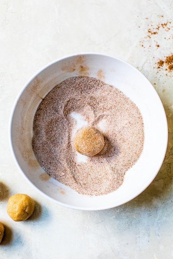 A simple sugar cookie dough is rolled in sugar and pumpkin pie spice to make these soft and chewy Pumpkin Snickerdoodles. A ball of pumpkin snickerdoodle dough rolled in cinnamon sugar