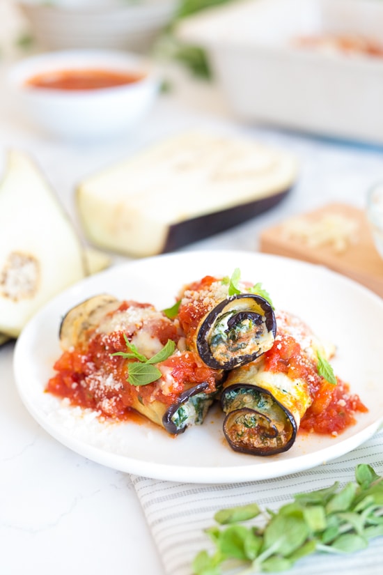 This low-carb eggplant rollatini recipe with creamy ricotta, spinach, savory marinara, and mozzarella is a satisfying vegetarian dinner. Three eggplant rollatini with sauce on a plate.