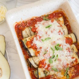 Overhead view of baked eggplant rollatini in a baking dish.