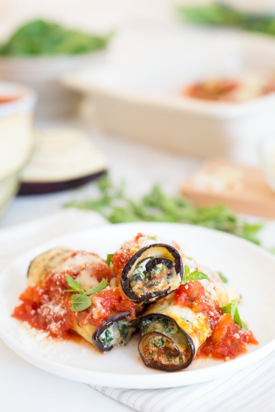 This low-carb eggplant rollatini recipe with creamy ricotta, spinach, savory marinara, and mozzarella is a satisfying vegetarian dinner. Three eggplant rollatini with sauce on a white plate.