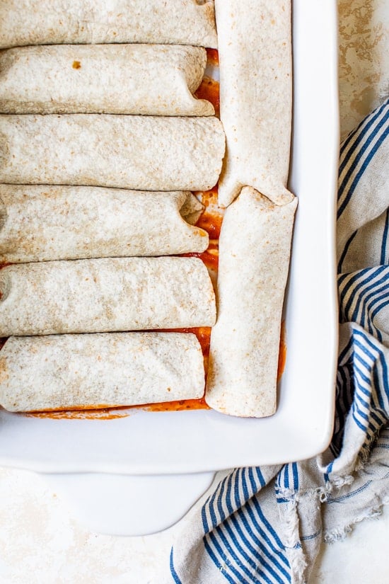 Easy vegetarian enchiladas made with butternut squash and black beans, smothered with enchilada sauce and cheese, then baked in the oven. A delicious recipe that's perfect for meatless Mondays!