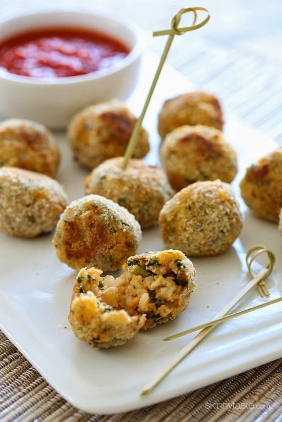 A plate of baked arancini rice balls with a dish of marinara sauce