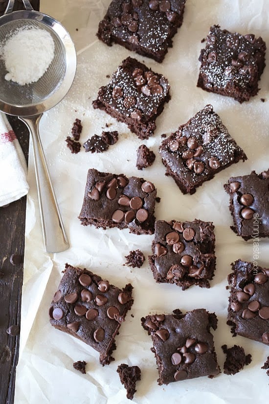 Overhead view of chocolate chip black bean brownies on parchment paper with dusting of powdered sugar