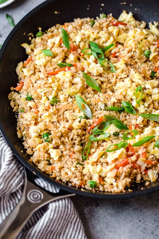 This low-carb cauliflower fried rice recipe is quick, flavorful and a great way to enjoy your favorite takeout-style dish in a lighter way! Cauliflower fried rice in skillet with vegetables and eggs.