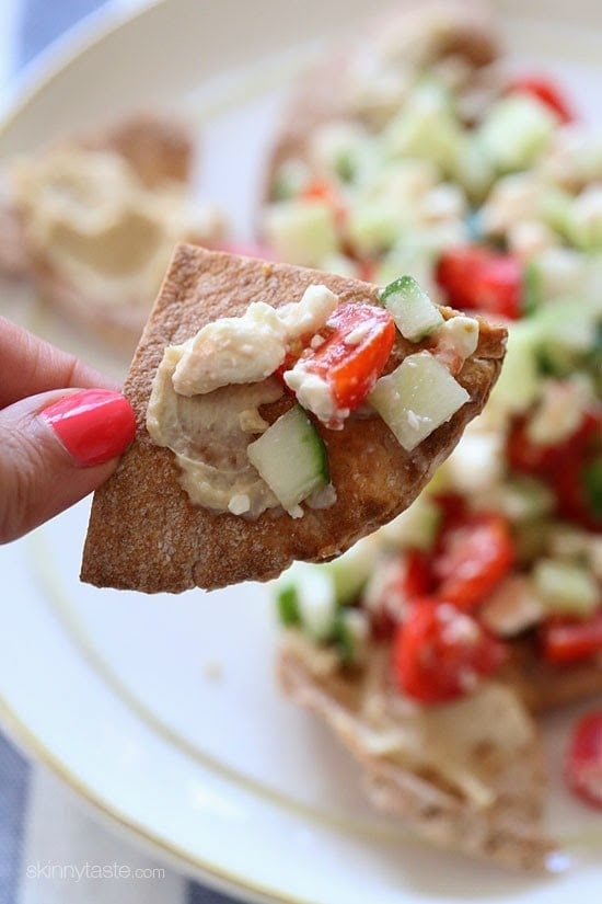 Greek Nachos These Greek Nachos are a healthier Greek twist on traditional nachos. They are made with whole wheat pita chips, hummus, cucumbers, tomatoes and feta.