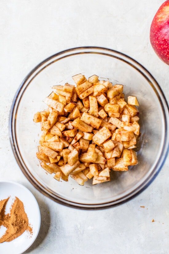 Moist apple bread recipe made with homemade applesauce, fresh apple chunks, spices, and walnuts in every bite. It's easy and so delicious! Overhead view of diced apples tossed with lemon juice, cinnamon, and agave in a bowl.