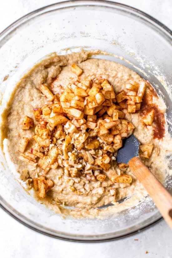 Moist apple bread recipe made with homemade applesauce, fresh apple chunks, spices, and walnuts in every bite. It's easy and so delicious! Folding diced apples and walnuts into apple bread batter.
