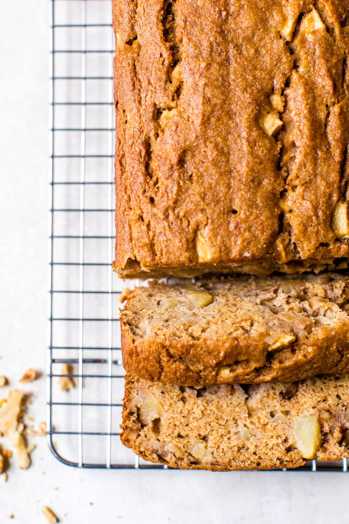 Moist apple bread recipe made with homemade applesauce, fresh apple chunks, spices, and walnuts in every bite. It's easy and so delicious! Overhead view of baked apple bread on a wire rack with slices cut from the end.