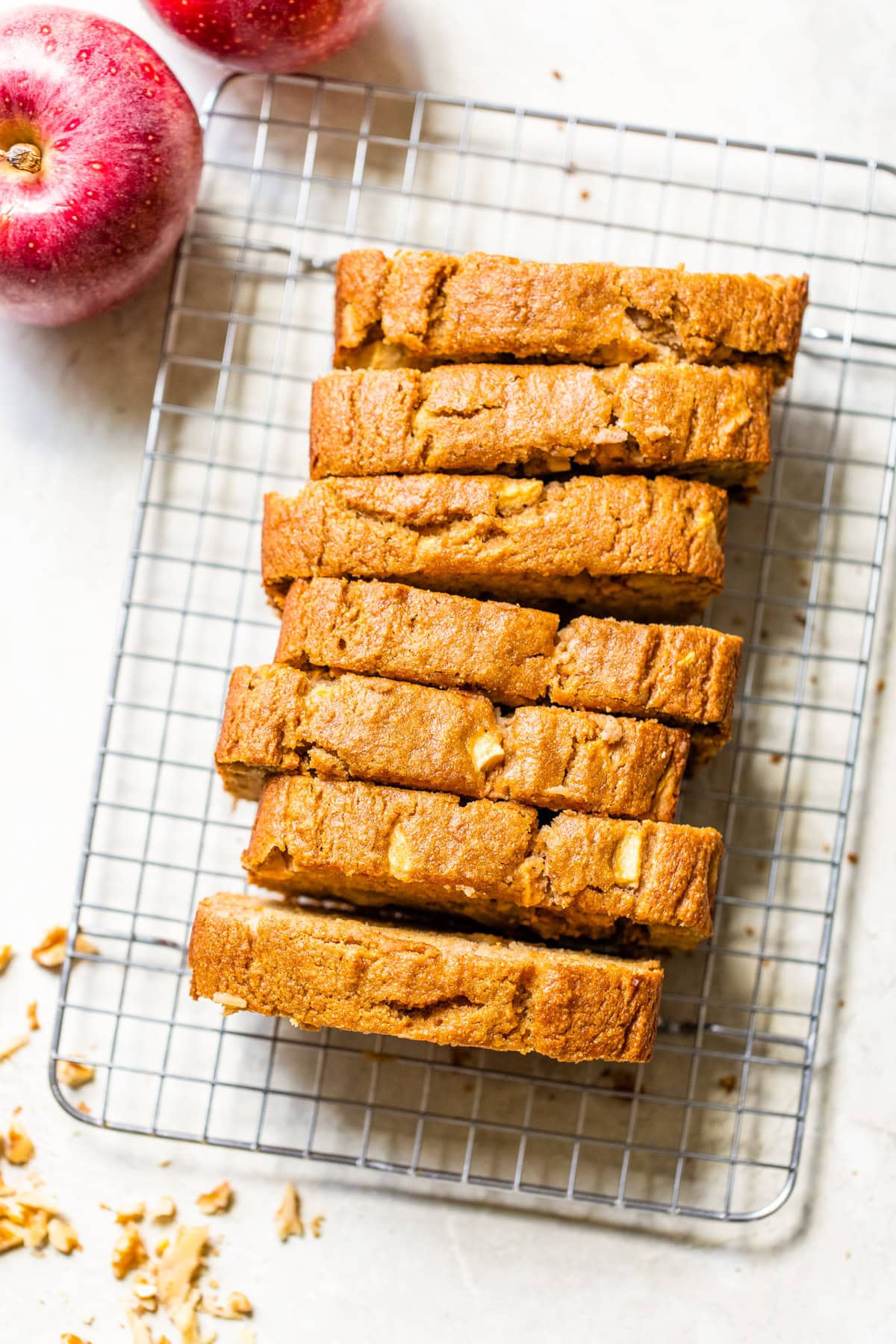 Moist apple bread recipe made with homemade applesauce, fresh apple chunks, spices, and walnuts in every bite. It's easy and so delicious! Overhead view of an apple bread loaf sliced on a wire rack.