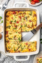 Breakfast casserole in baking dish with one portion removed.