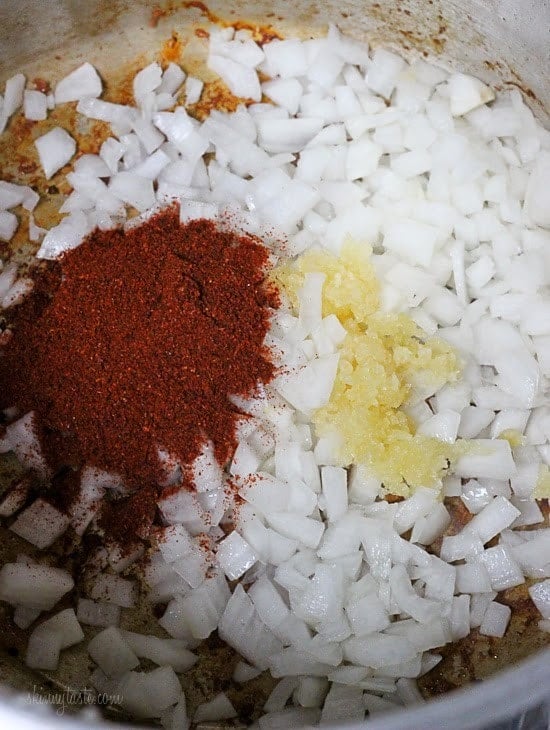 This Instant Pot Pozole Rojo recipe is easier and faster than the classic version! With pork, hominy and spices, it's hearty and flavorful. Onions with garlic and chili powder in Instant Pot.
