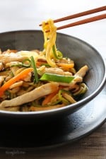Chopsticks holding a zucchini noodle over a bowl of Chicken zoodle lo mein.