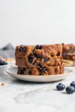 Stack of 3 blueberry banana bread slices on plate.