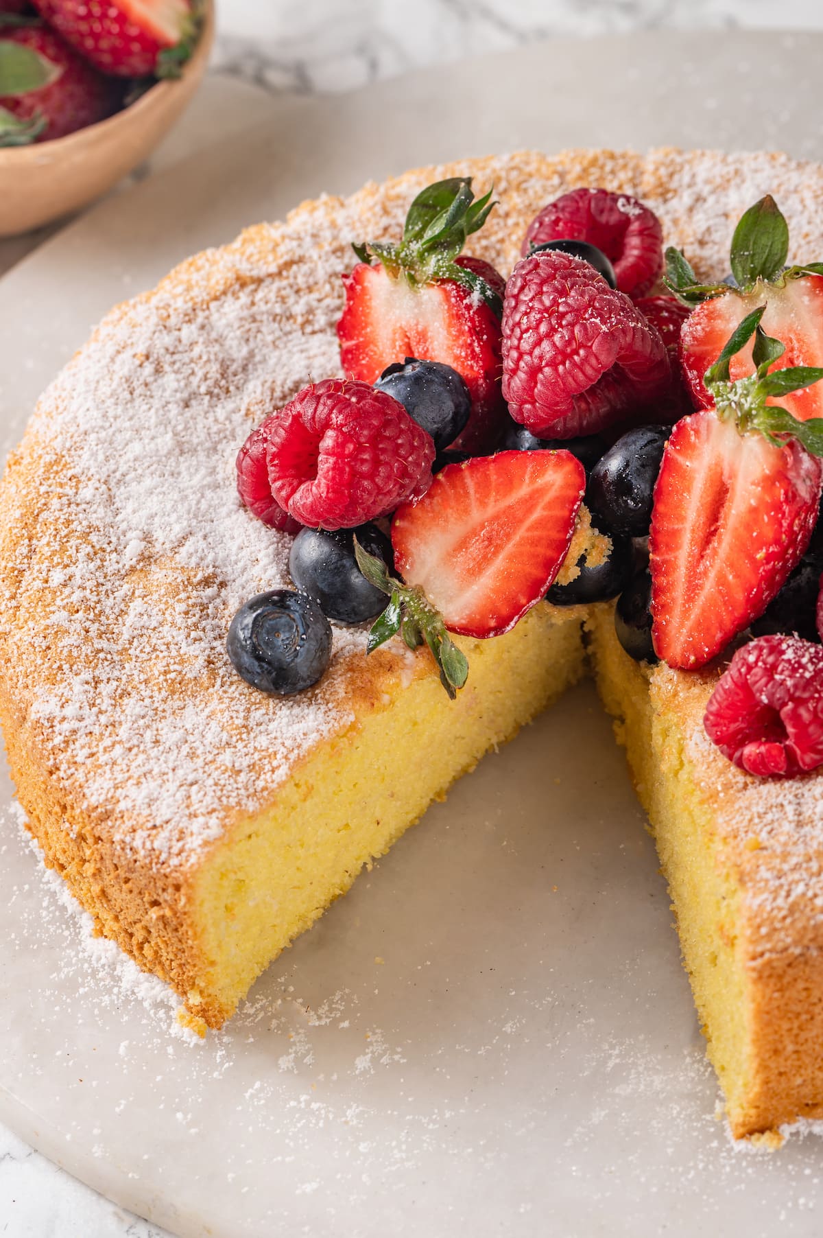 This easy almond cake recipe is made with just 5 ingredients but don't let its simplicity fool you—it's light, airy, and so delicious! Almond cake on platter with slice removed