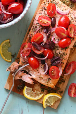 Grilled wild cedar plank salmon with fresh herbs topped with tomatoes, kalamata olives and red onion. This is so flavorful, and simple to make, perfect for weeknight cooking or fancy enough to serve if you're having guests. Aside from soaking the plank in water, the rest takes under 30 minutes to make.