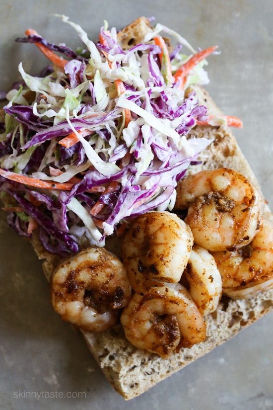 This homemade take on a Louisiana-style shrimp po boy sandwich uses sautéed shrimp and a light, creamy cabbage slaw on whole wheat bread. Overhead view of a shrimp po' boy assembled on French bread.