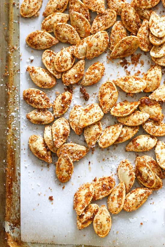 These Spicy Pumpkin Seeds are a fun twist on roasted pumpkin seeds. They make a tasty, filling snack on their own and a great salad topper. Spicy pumpkin seeds on a baking sheet