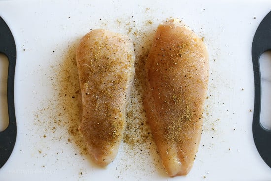 Instant Pot salsa chicken is so quick and easy! Make this juicy 2-ingredient shredded chicken to use in tacos, rice bowls, salads, and more. Two seasoned chicken breasts side by side on a cutting board.