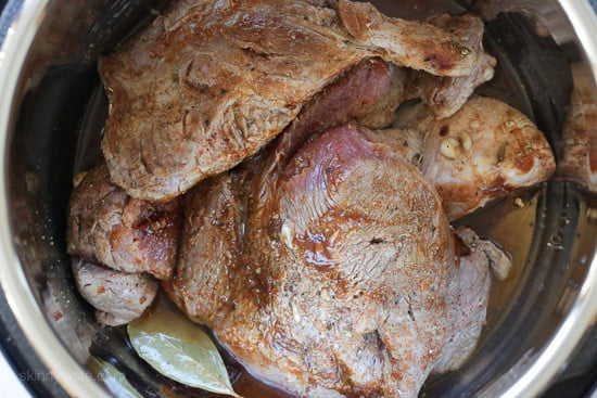 The best Instant Pot Carnitas recipe! Make juicy Mexican pulled pork in the pressure cooker for tacos, burrito bowls, taco salads, and more. Browned pork shoulder inside the Instant Pot with broth and bay leaves.