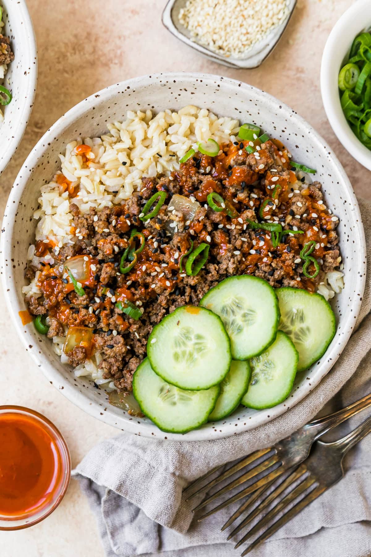 An easy and delicious Korean beef recipe is made with ground beef, served over rice with cucumbers and gochujang sauce. A bowl filled with homemade Korean beef, rice and cucumbers.