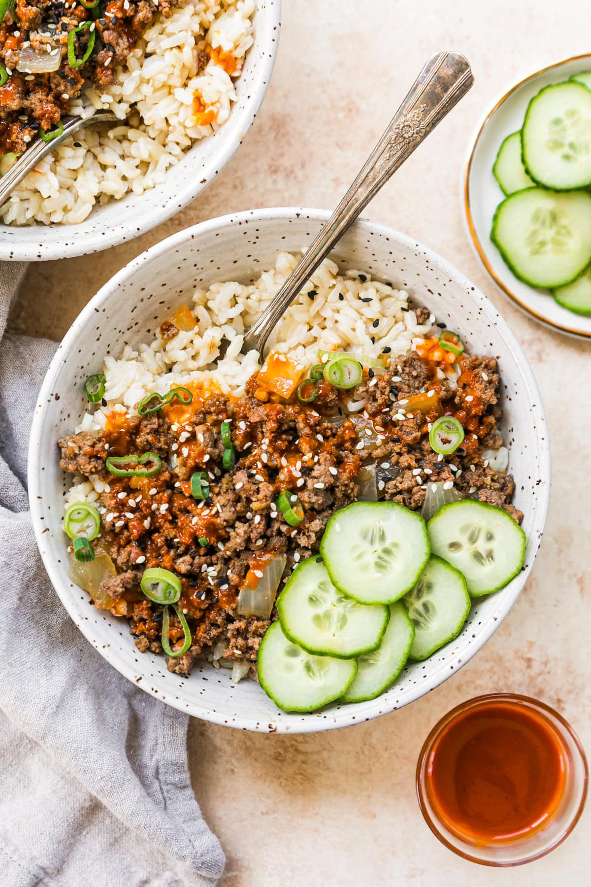 An easy and delicious Korean beef recipe is made with ground beef, served over rice with cucumbers and gochujang sauce. Korean beef in a bowl with rice and cucumber slices.