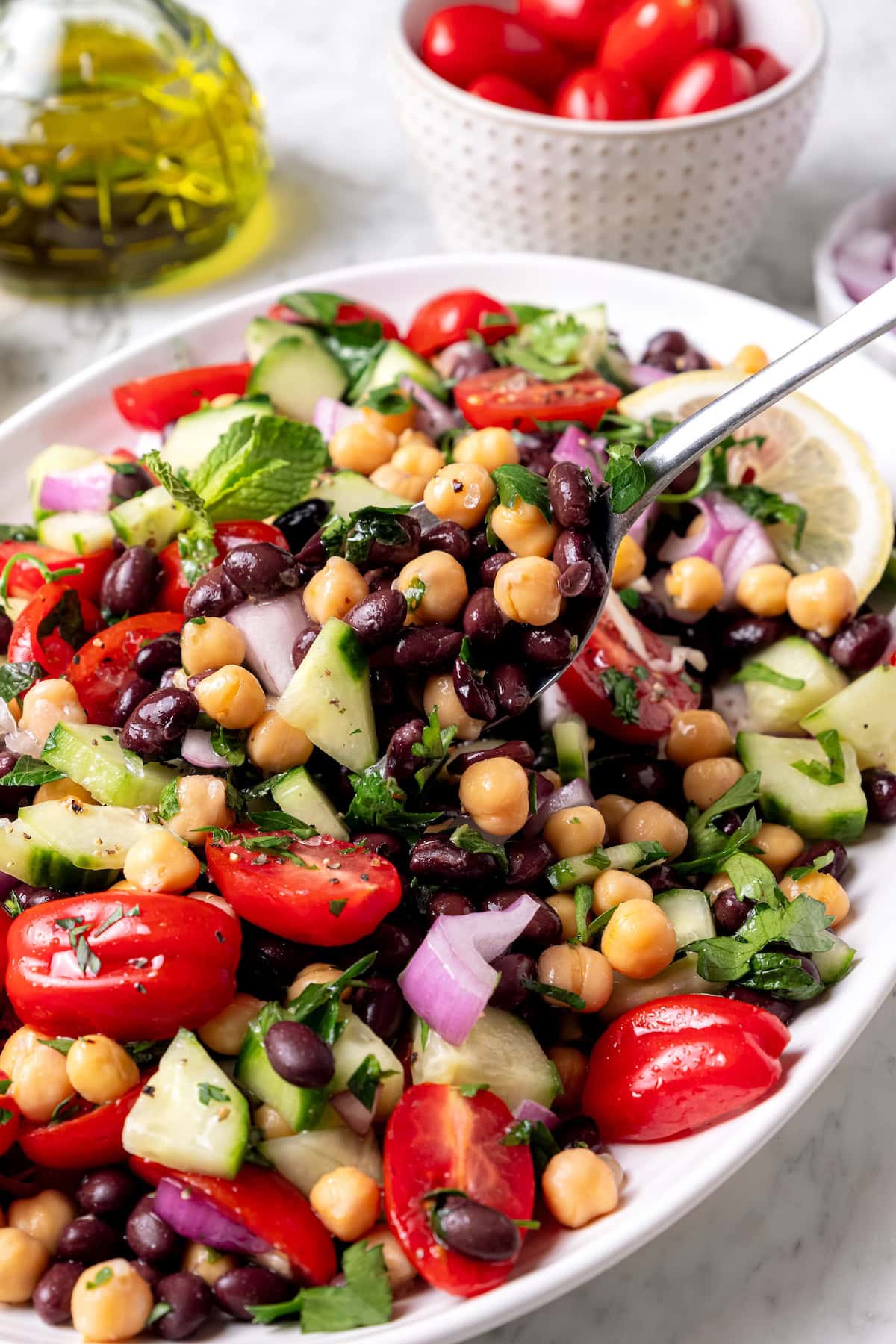 This easy garbanzo bean Mediterranean salad is fresh, simple, and full of flavor, made with minimal prep and wholesome ingredients. Garbanzo bean Mediterranean salad in serving spoon held over bowl.