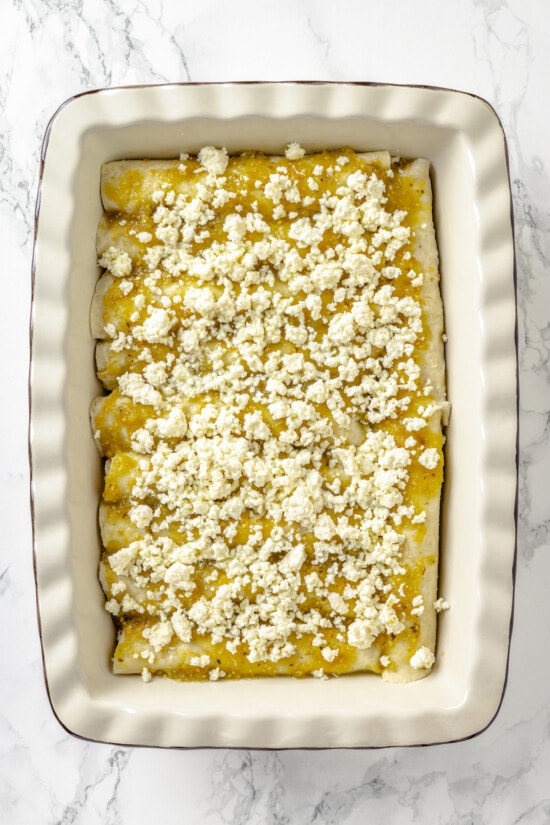 These Chicken Enchiladas Verdes (aka Green Enchiladas) are made with white corn tortillas, salsa verde, chicken breast, and queso fresco. Queso fresco on top of salsa verde on enchiladas