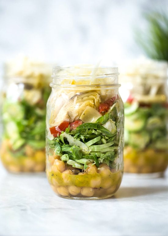 A quick and easy salad in a jar made with shaved Brussels sprouts, chickpeas, marinated artichokes, sun dried tomatoes and Asiago cheese. Perfect to pack for work or anywhere you need a portable lunch on-the-go! To serve you simply shake it up and pour it into a bowl.