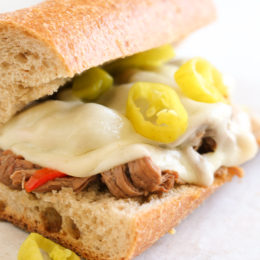 Set it and forget it with this easy slow cooker sandwich recipe. Top round roast, bell peppers, pepperoncini, garlic and dried herbs slow cooked all day then shredded and served on whole wheat Italian bread or rolls with melted provolone.
