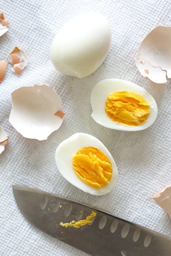 Hard boiled eggs cut in half with their shells next to them