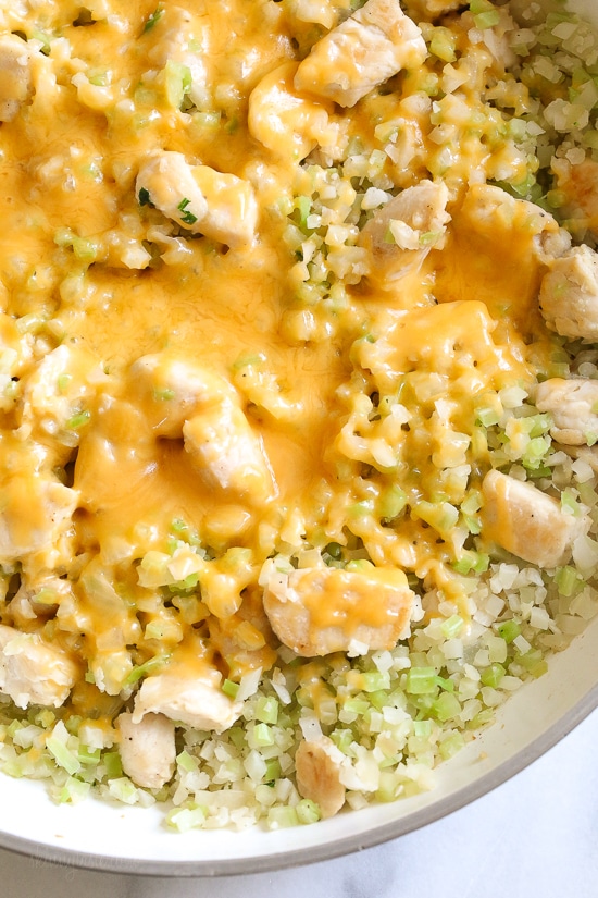 Skillet Cheesy Chicken and Veggie "Rice" made with riced broccoli and cauliflower, sauteed chicken and cheddar cheese. It's so fast and easy to make!
