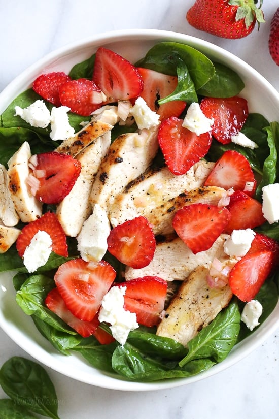 Make this high-protein strawberry chicken salad with fresh spinach, berries, goat cheese, and grilled chicken drizzled with balsamic dressing. Overhead view of a strawberry chicken salad with spinach and goat cheese in a bowl.