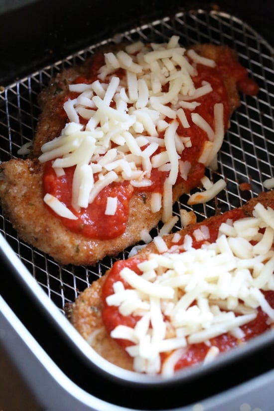 Quick and cheesy air fryer chicken parmesan is an easy, weeknight-friendly dinner. A lighter spin on the classic Italian chicken dish! Chicken parmesan inside the air fryer topped with shredded mozzarella cheese.
