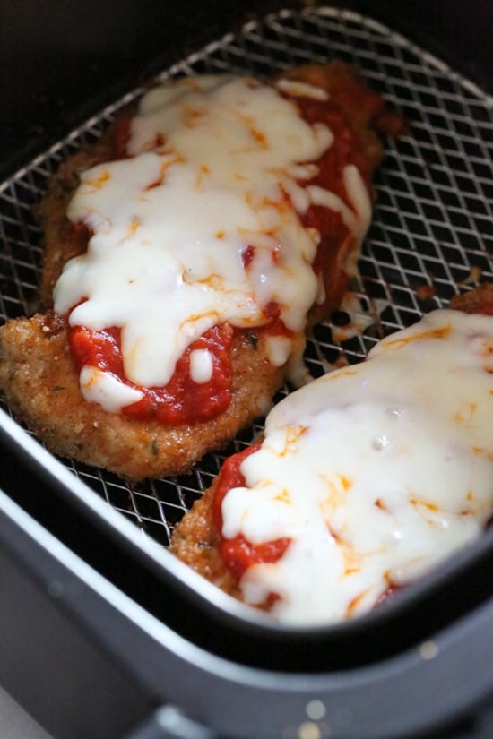 Quick and cheesy air fryer chicken parmesan is an easy, weeknight-friendly dinner. A lighter spin on the classic Italian chicken dish! Close up of air fryer chicken parmesan inside the air fryer basket.