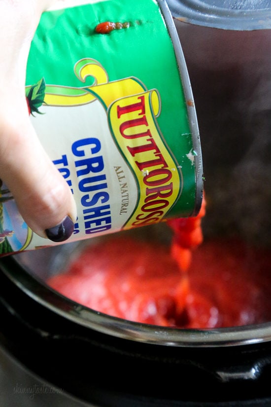 Instant Pot Bolognese sauce is full of flavor and ready in one hour! See how easy it is to make a classic meat sauce in your pressure cooker. A can of crushed tomatoes is poured into the Instant Pot.