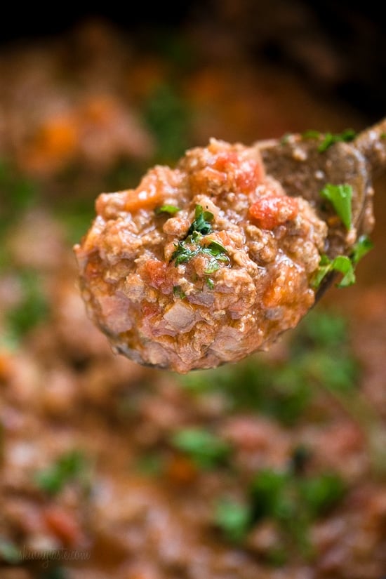 Instant Pot Bolognese sauce is full of flavor and ready in one hour! See how easy it is to make a classic meat sauce in your pressure cooker. Close up of a spoonful of bolognese sauce held over a pot of sauce.