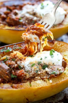 A forkful of spaghetti squash lifted from a roasted spaghetti squash half stuffed with beef and mushroom ragu.