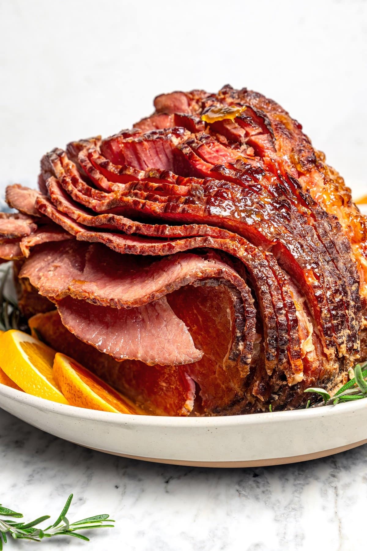 Slow Cooker Ham is the easiest main dish for the holidays! A two-ingredient glaze and a crockpot are all you need for moist, flavorful ham. Slow cooker spiral ham on platter with orange slices.